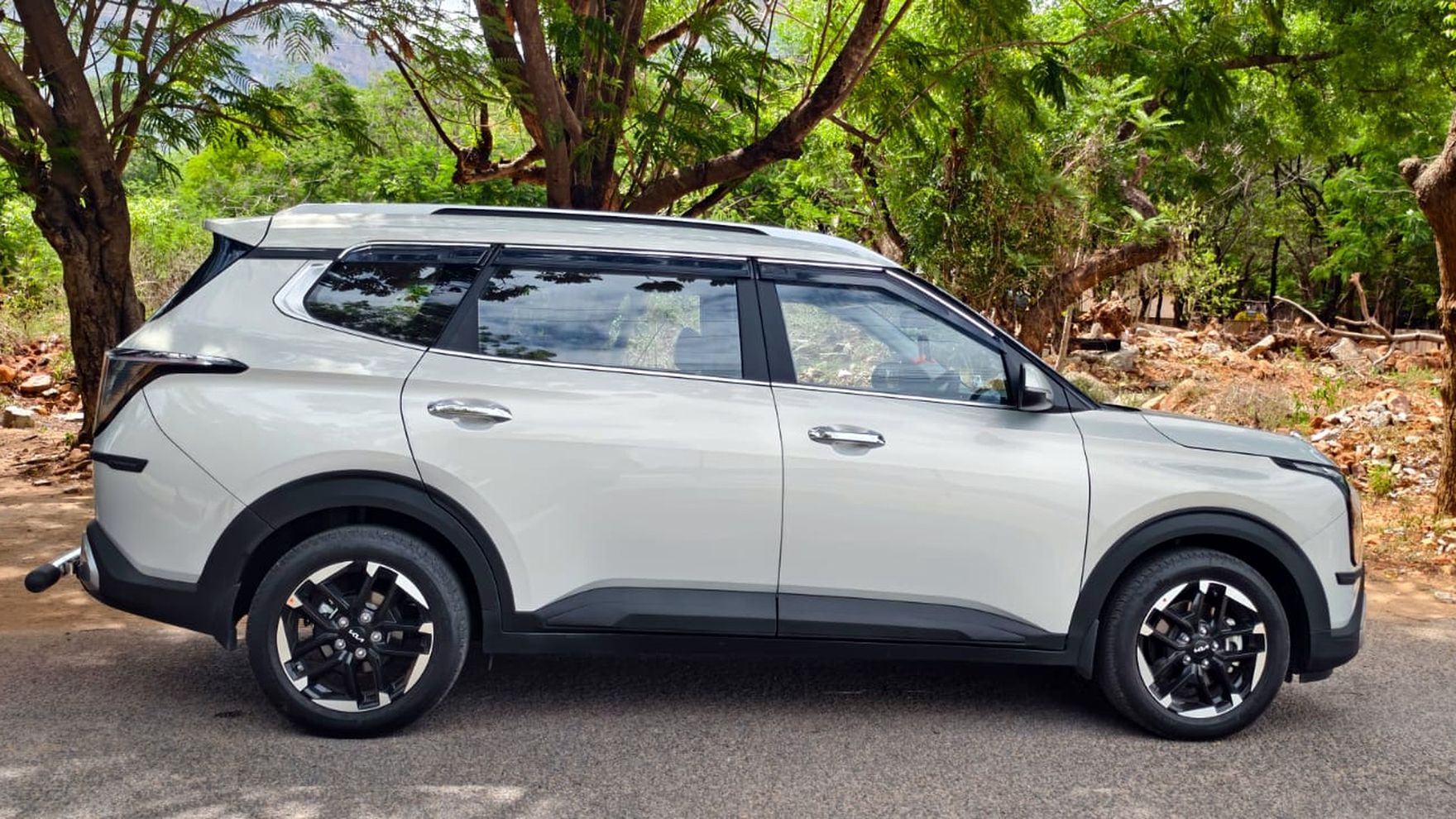 Kia Carens from our fleet parked on a tree-lined road near Tirupati